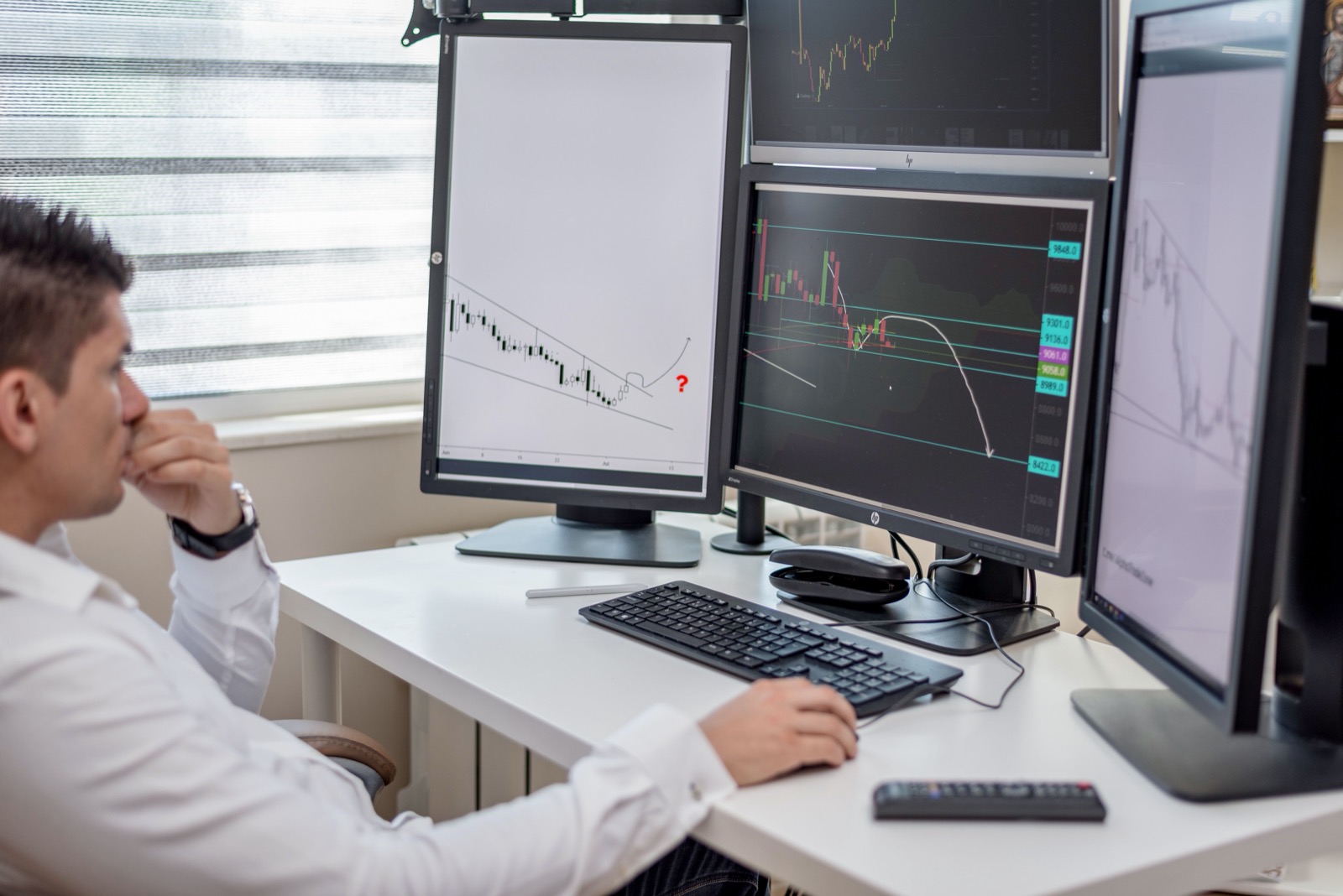 A trader studying several monitors of price charts