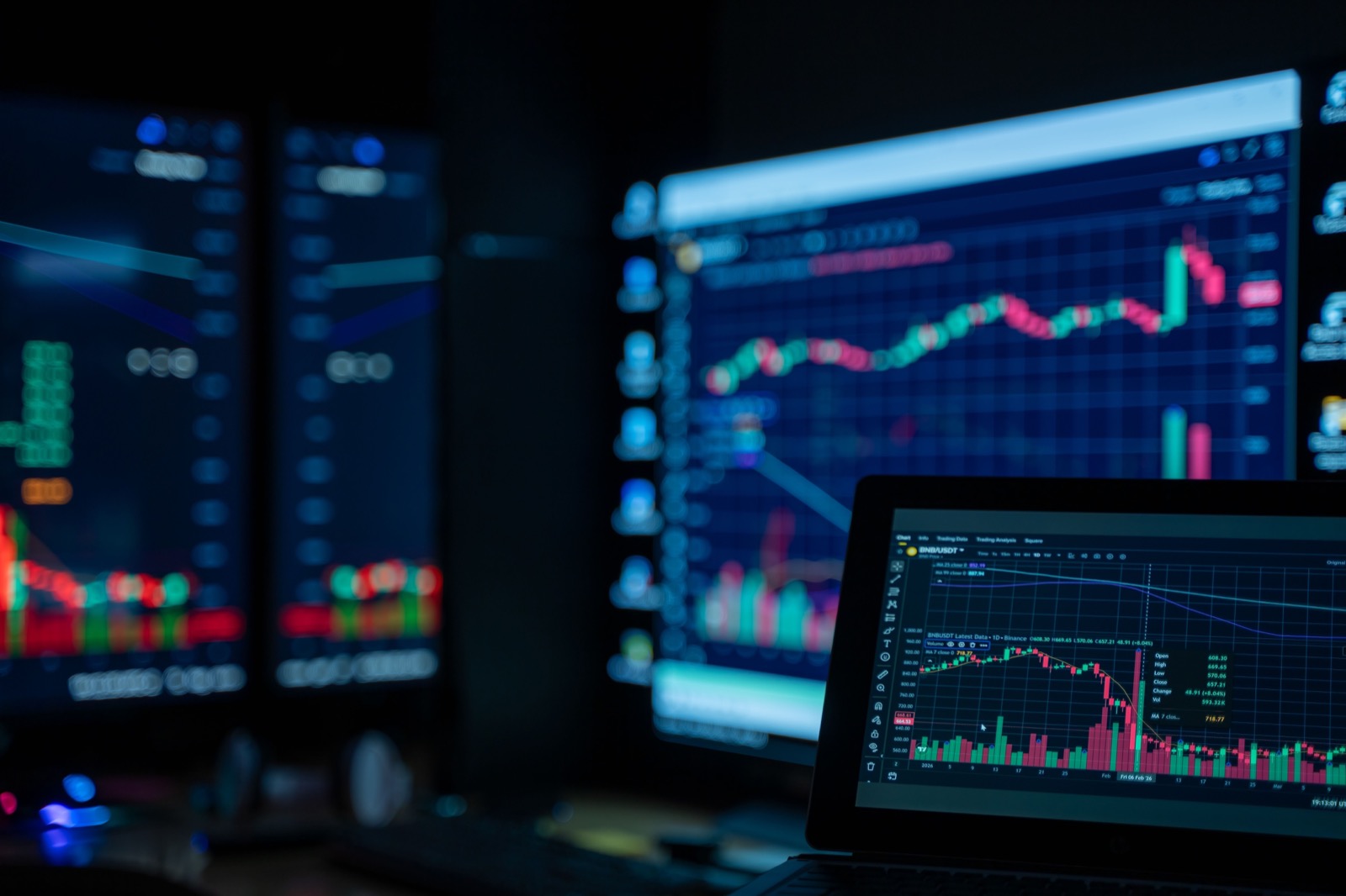 Layar trading menyala di ruangan gelap yang kosong, grafik tetap berjalan tanpa ada orang di meja
